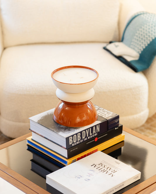 Bougie TamTam Twist Narguillé posée sur une pile de livres d'art, table basse et canapé bouclé écru