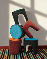 Poufs Léa Tangerine et Bleu Sarah en velours empilés sur un tapis rayé, collection Playground